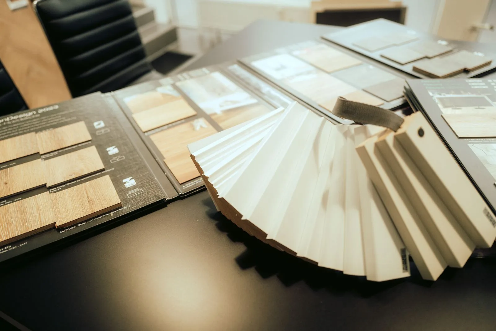 Aufgefächerte Materialproben neben einem aufgeschlagenen Musterbuch mit Holzdekoren