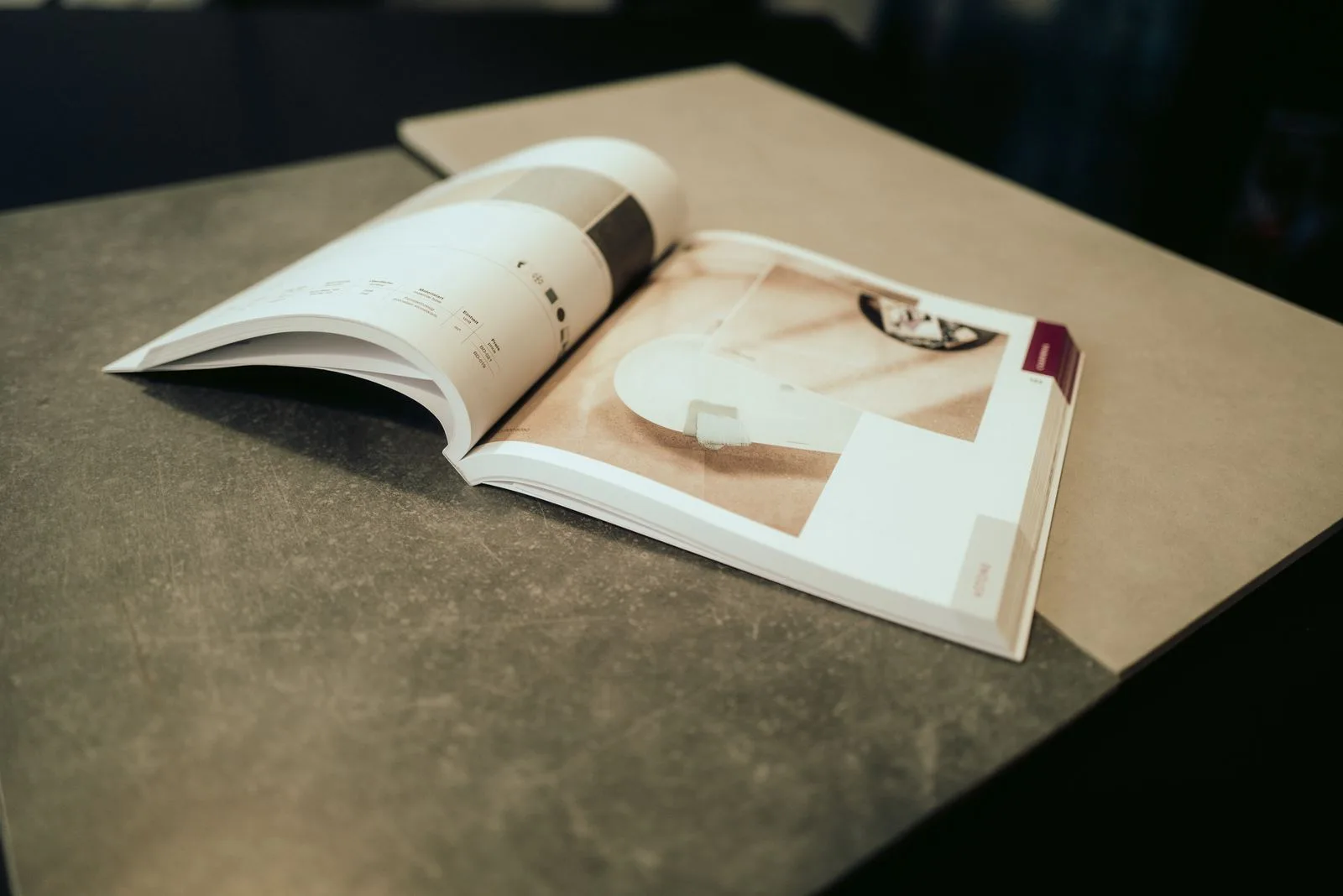 Aufgeschlagener Fliesenkatalog auf einer Tischplatte in Betonoptik im Beratungsbereich