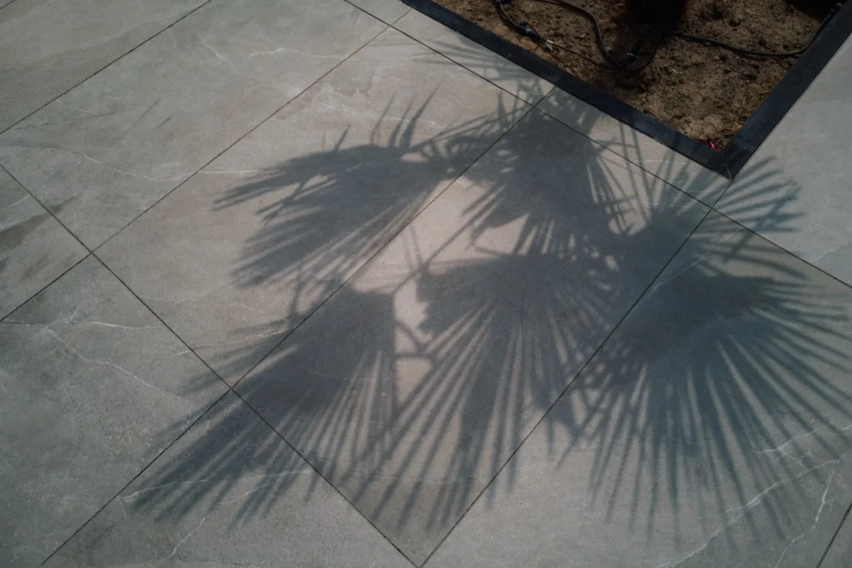 Terrassenplatten in Steinoptik mit dem Schattenwurf einer Palme