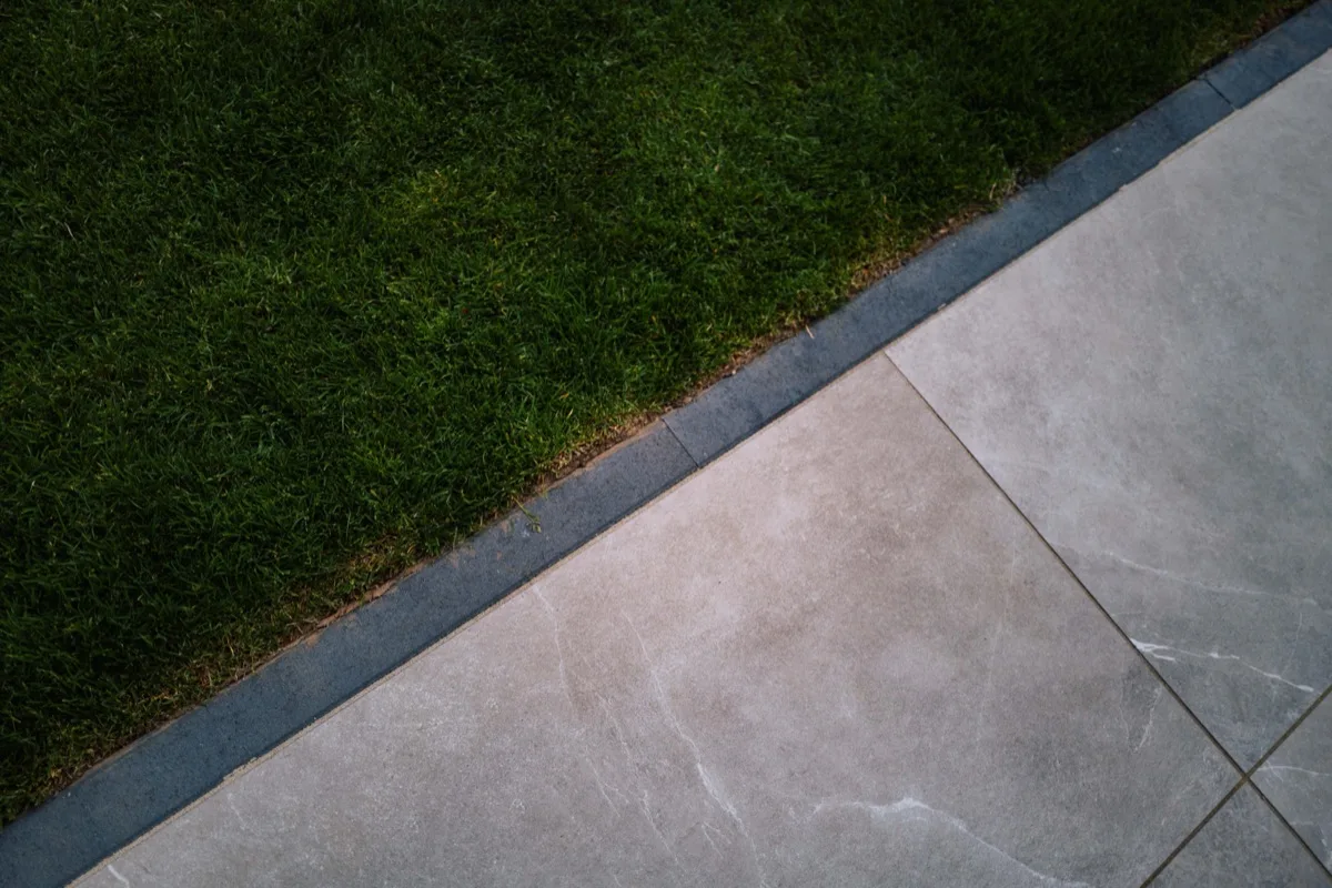 Terrassenplatten in heller Steinoptik mit sauberer Randeinfassung zur Rasenkante