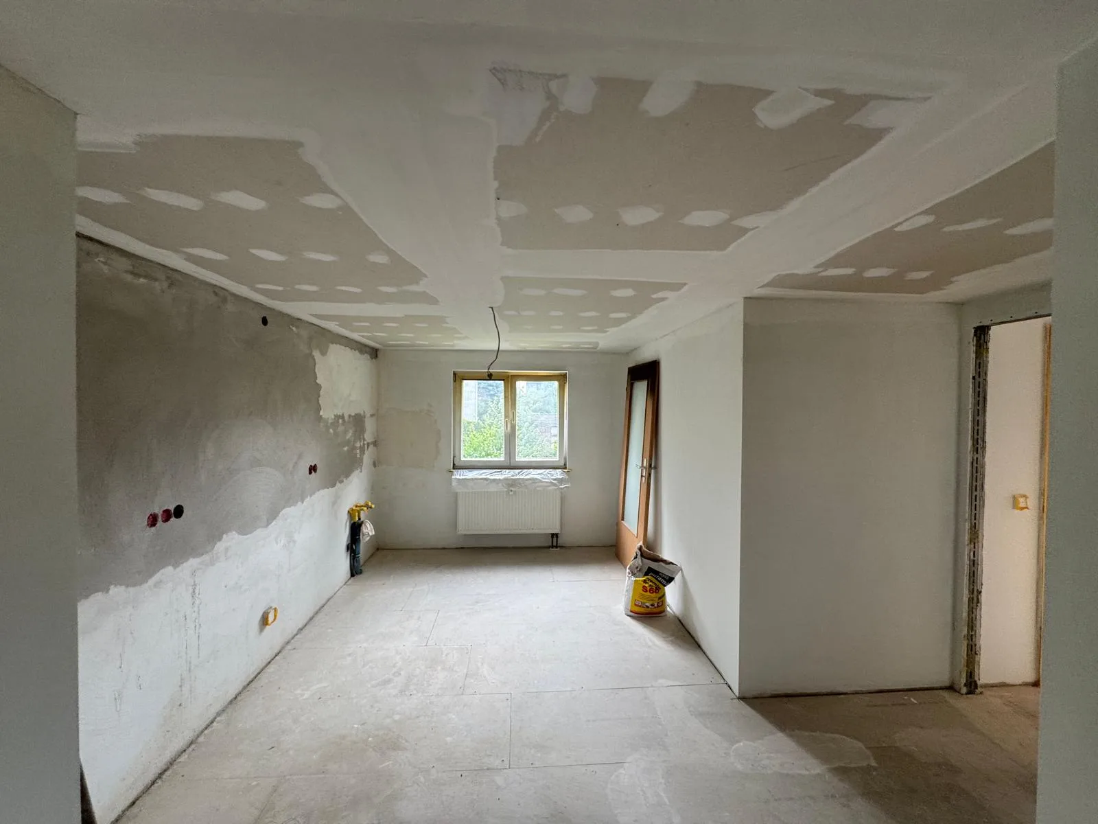 Wohnraum im Ausbau mit frisch verspachtelter Gipskartondecke und vorbereiteten Wänden
